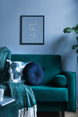 Grey luxury interior with green velvet sofa, pillows, pouf, blanket and tropical plant. Modern composition with mockup image. Brown wooden parquet.
