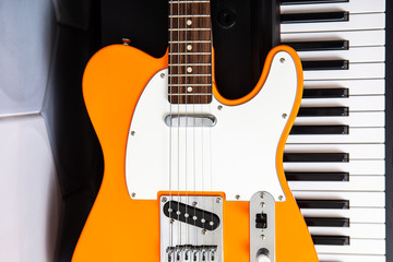 guitar deck in front of of piano keys, closeup top view