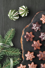 Obraz na płótnie Canvas Star-shaped chocolates on dark textured background with Christmas tree twigs