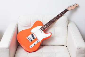 Orange electric guitar on a leather armchair