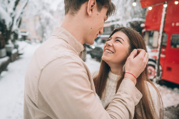 young guy and beautiful girl kiss in a snowy park. Couple in sweaters.