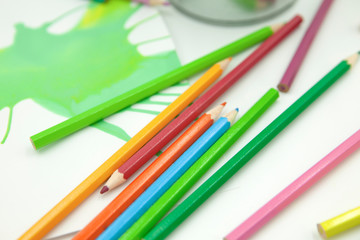 lápices de colores desordenados con pintura abstracta verde en fondo blanco