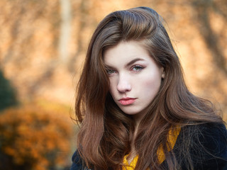 Fototapeta premium Fabulous redhead woman with long hair in yellow sweater black leather jacket on blurred autumn background.