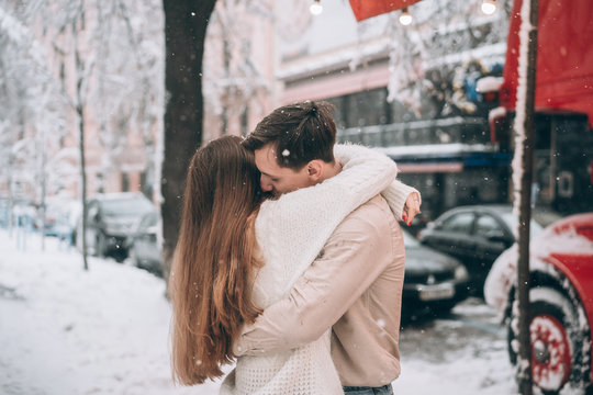 young guy and beautiful girl kiss in a snowy street