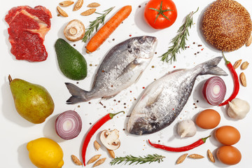 Healthy food clean eating selection: fruit, vegetable, seeds, fish, meat, leaf vegetable on white background. Top view.