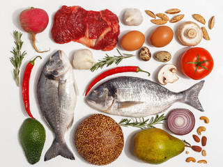 Healthy food clean eating selection: fruit, vegetable, seeds, fish, meat, leaf vegetable on white background. Top view.