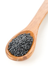 Heap of black organic beluga lentils in wooden spoon on white