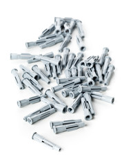 Heap of unused, new, grey plastic wall plug bolts over white