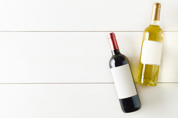 Red and white wine bottle on white wooden table flat lay from above
