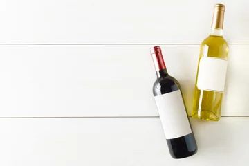 Keuken foto achterwand Rode en witte wijnfles op witte houten tafel plat gelegd van bovenaf © Shawn Hempel