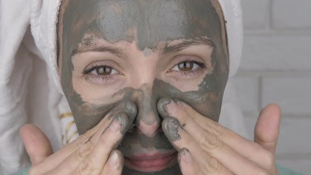 Funny woman applying clay mask. Close-up of a woman's face applying a clay mask to her face.