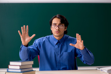 Young male teacher in front of chalkboard  