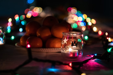 Mandarynki i świeczka na tle świątecznych światełek