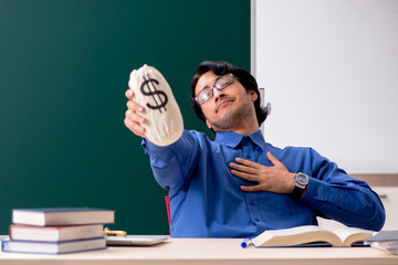 Young male teacher in front of chalkboard  