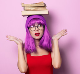 Portrait of young style hipster girl with purple hair and books on purple color background