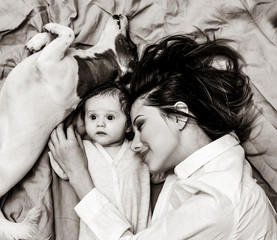 young mother and a little child with dog lying down on bed background . Image in black and white color style