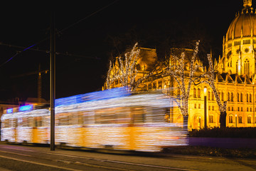 Festively decorated light tram ,Fenyvillamos, on the move with Parliament of Hungary at Kossuth square by night. Christmas season in Budapest, Hungary