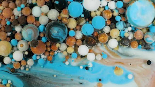 Colorful paint in bubbles organically moves in the liquid