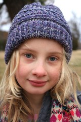 Portrait of a young blond blue eyed girl wearing a purple beanie hat in the cold