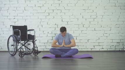 disabled man doing yoga, wheelchair and exercise mat
