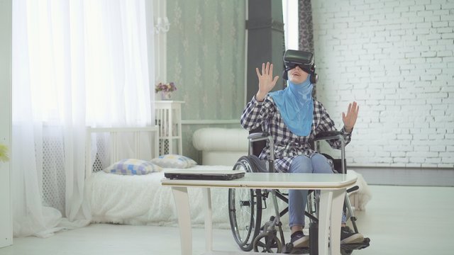 woman in hijab , wheelchair, uses VR glasses, 3D technology, virtual travel - Powered by Adobe