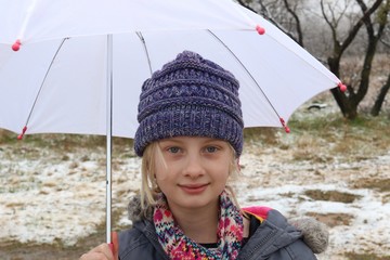 Portrait of a young girl in the snow holding a white umbrella
