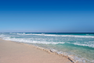 Fototapeta na wymiar Ocean waves, wet sand and blue sky