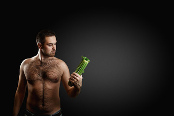 Hairy bearded caucasian man holding a bunch celery isolated on dark grey background