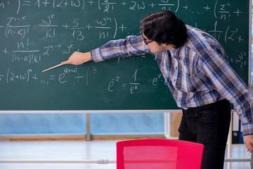 Young funny math teacher in front of chalkboard 