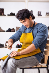 Young man repairing shoes in workshop 