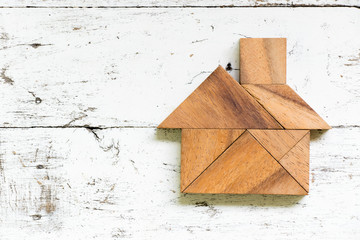 Tangram puzzle in home shape on old white wood background