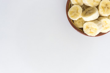 Bowl with banana slices on white background