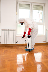 Exterminator in work wear spraying pesticide or insecticide