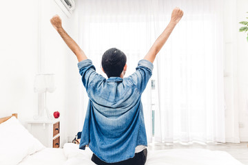Man sitting near the window and stretching in bed after wake up.man happy and relaxed breathing fresh air at morning