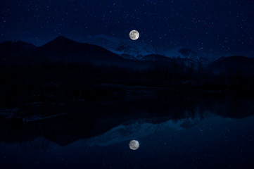 Landscape of gorgeous full moon over the snow-capped mountains reflected in the lake or mysterious night sky with full moon. Azerbaijan