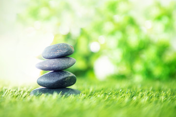 Obraz na płótnie Canvas balance with a pyramid of stone on fresh nature green grass , spa meditation or well-being with zen concept