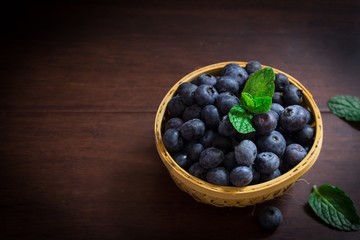 Fresh Blueberries in a basket on dark moody background, selective focus
