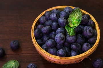 Fresh Blueberries in a basket on dark moody background, selective focus