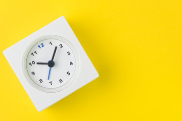Time, deadline or reminder and schedule concept, minimal modern square alarm clock with white face on yellow background in flat lay or top view, studio shot with copy space