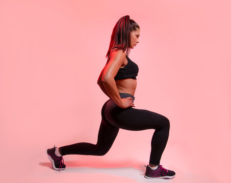 Side view young woman doing legs exercise, fitness steps , studio shot pink background 