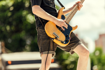 Close-up of bassist playing at an outdoor show - obrazy, fototapety, plakaty