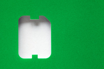green background with a hole in the shape of a sim card, copy space