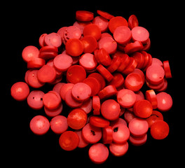 Natural red coral flat beads as red blood cells isolated on a black background