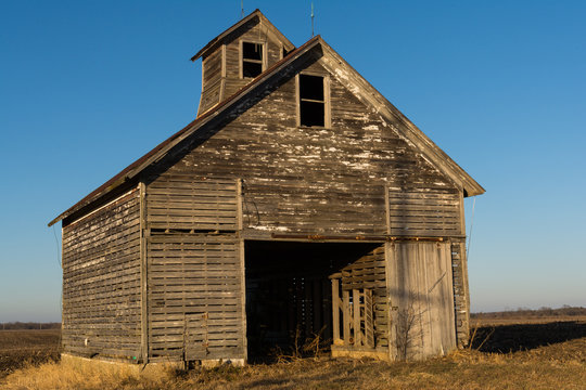 Old weathered wooden barn in open field on a Winter afternoon.  LaSalle County, Illinois, USA