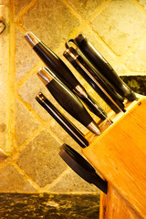 A closeup of a wooden block full of kitchen knives on a granite countertop.