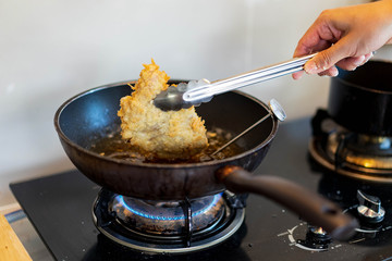 Cooking fried Japanese pork Tonkatsu homemade cutlet, handle pork by pinch and using temperature tool during cook on heat oil on pan.