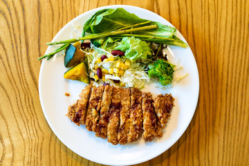 Japanese pork Tonkatsu homemade with fresh vegetable salad serve on table.