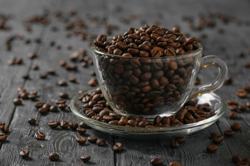 Glass coffee Cup with coffee beans on a black wooden rustic table.