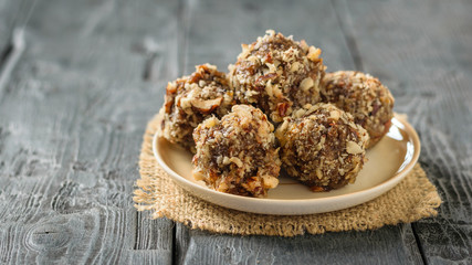 Homemade sweets made by hand from nuts, dried fruits and honey on a plate on a black table.