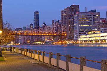 Naklejka premium Manhattan skyline and Queensboro Bridge across East River to Roosevelt Island. Pathway along the riverbank and skyscrapers of Manhattan, New York, USA.